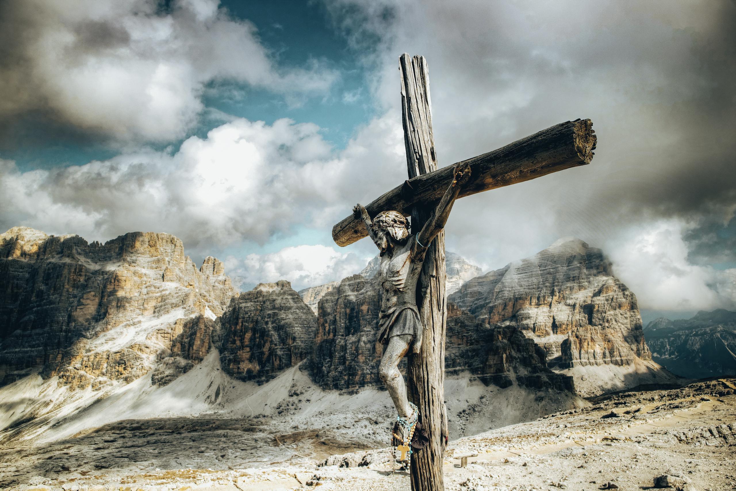 Wooden crucifix against a dramatic mountain backdrop with clouds.